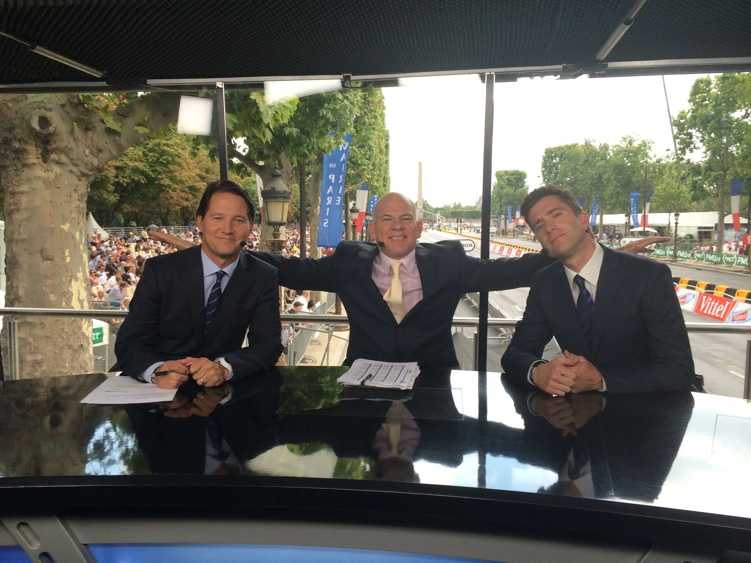 A four-person commentary desk set up outdoors at a cycling event.