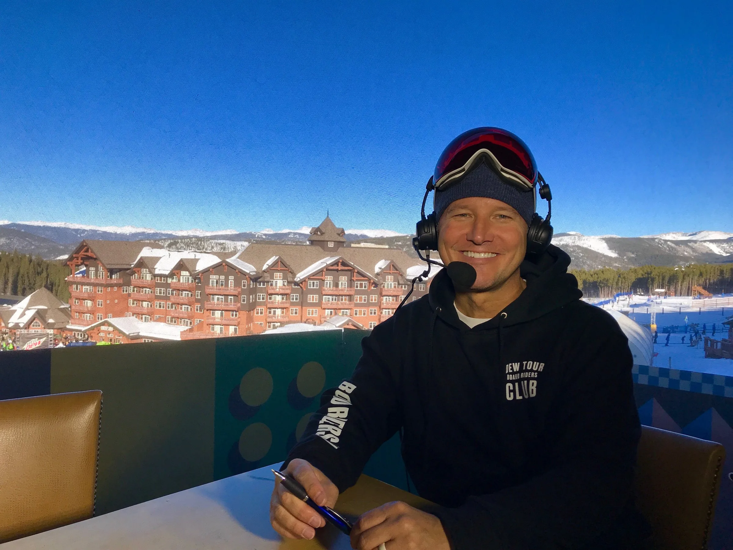 Todd Harris in goggles and a headset, calling an event from a mountainside position.